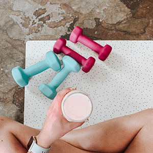 Top down view of woman working out with two sets of weights and a protein shake